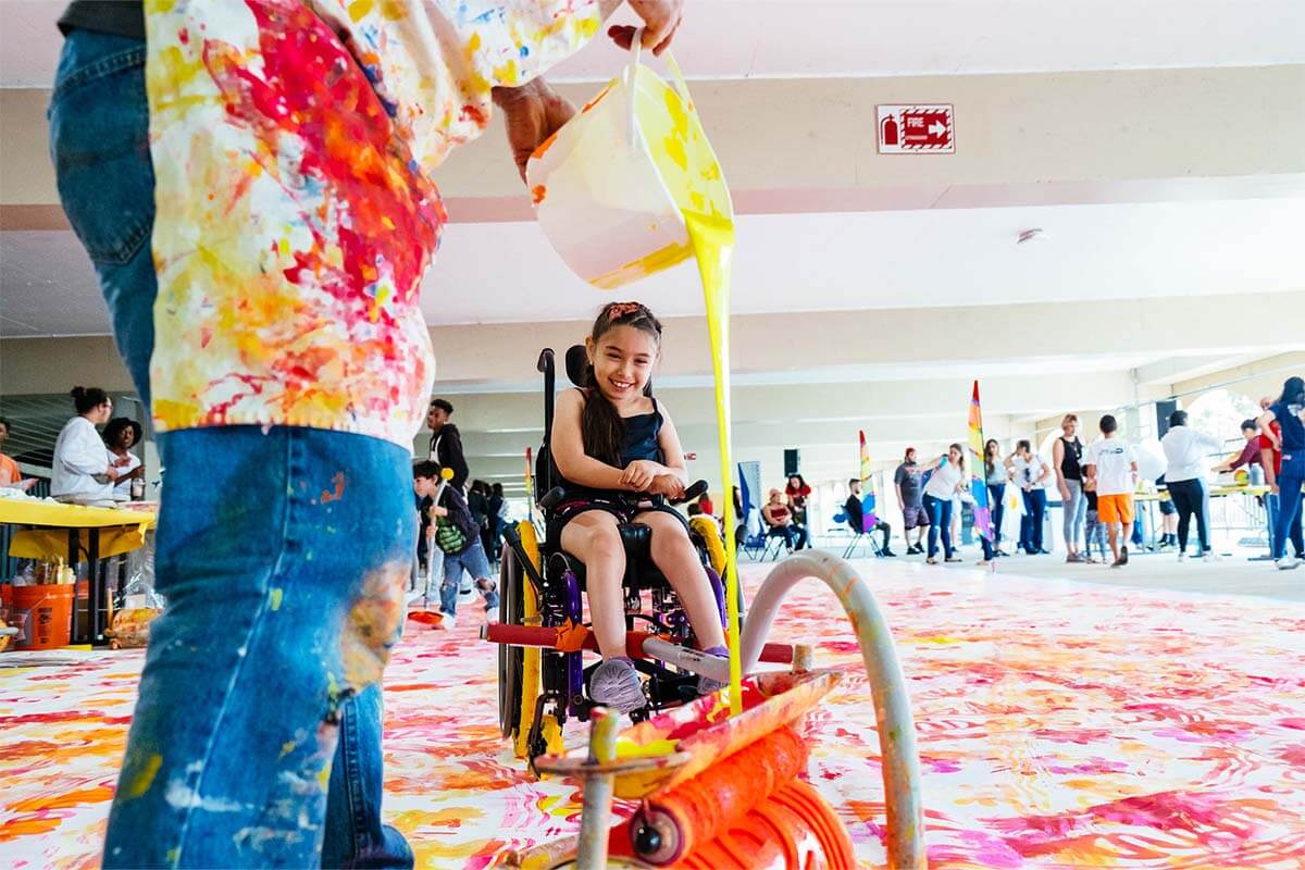 Child in a wheelchair playing with paint