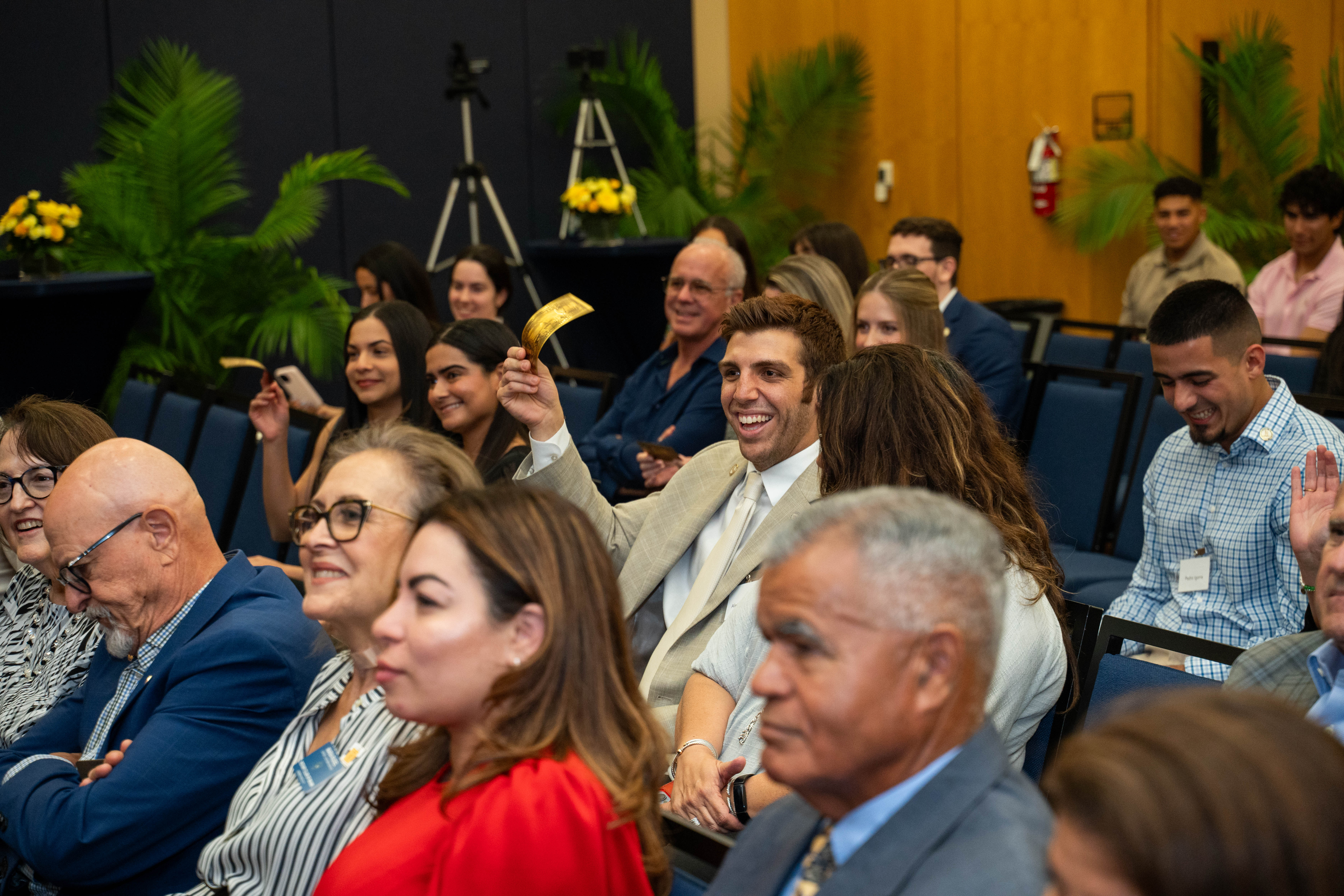 TBM Scholarship recipients wave golden $1M notes celebrating the million-dollar milestone.